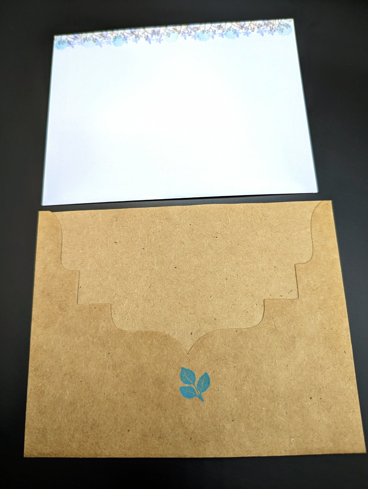 Handmade stationery card with a design resembling an autumn leaf on a brown background, paired with a beige envelope.