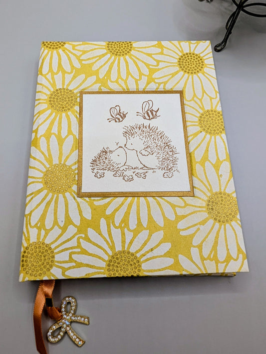 Artisan handmade hardcover journal featuring yellow Nepal daisy paper cover and orange ribbon charm.