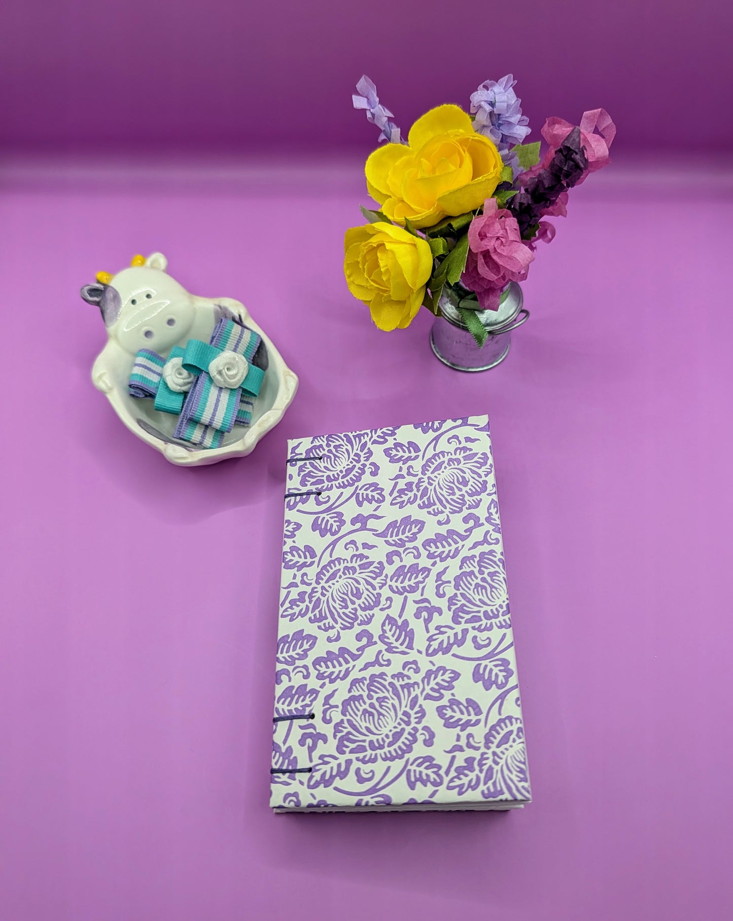 Handmade mini sketchbook featuring purple embossed flowers (Italian paper) and a decorative purple French Stitch. Shown front of the sketchbook.
