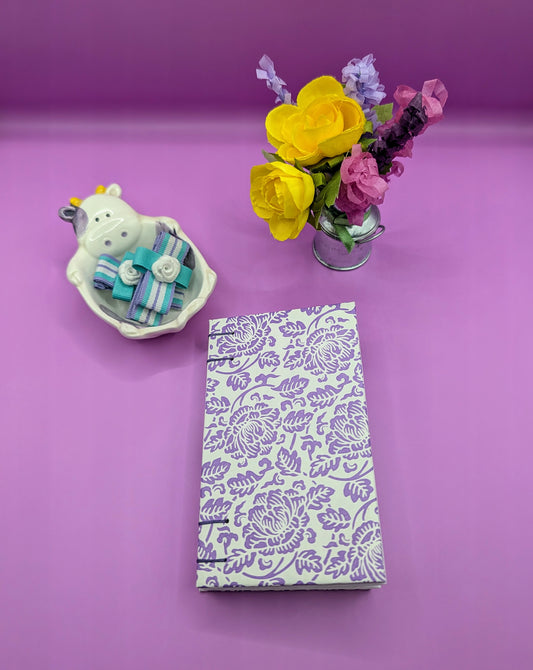 Handmade mini sketchbook featuring purple embossed flowers (Italian paper) and a decorative purple French Stitch. Shown front of the sketchbook.