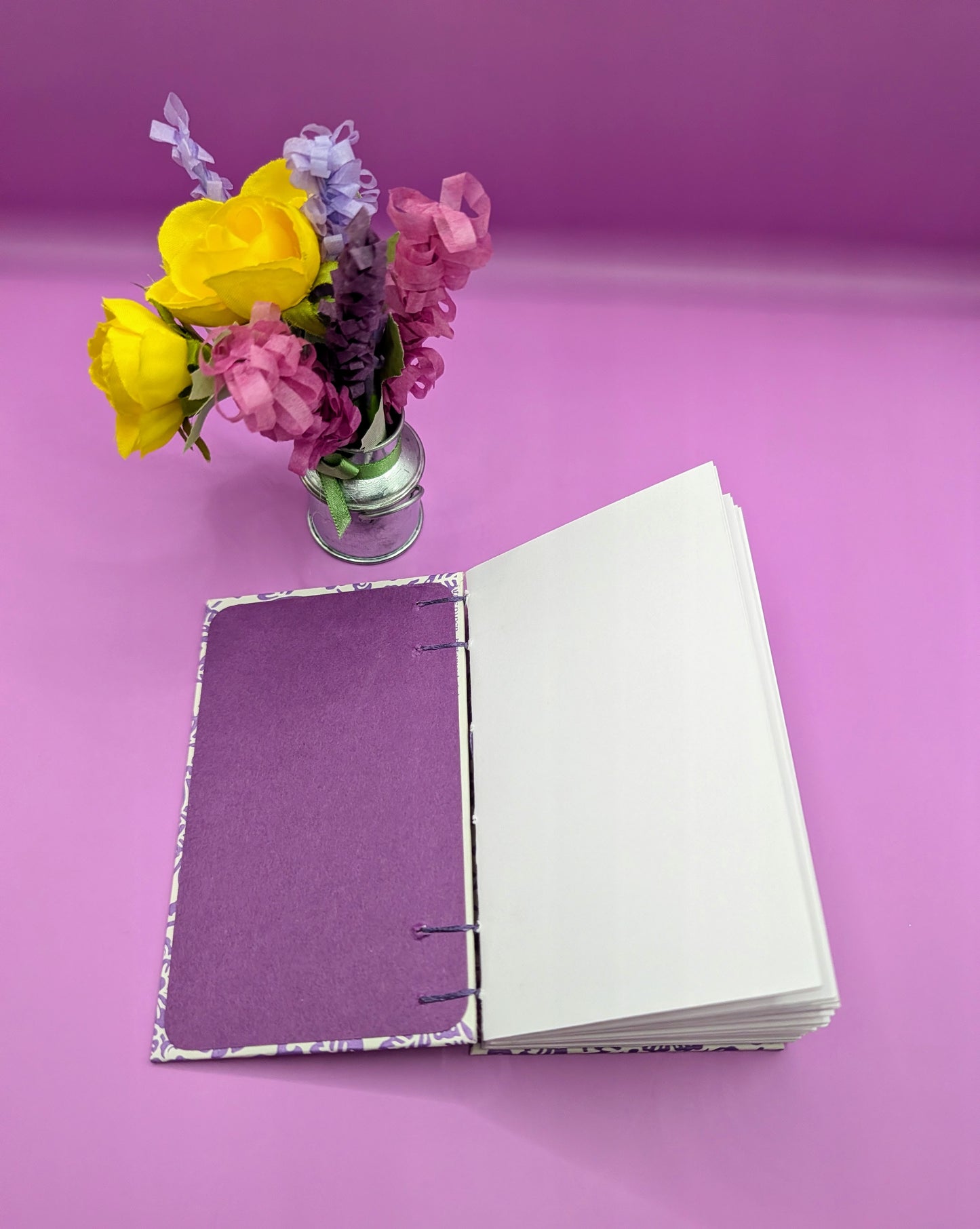 Handmade mini sketchbook featuring purple embossed flowers (Italian paper) and a decorative purple French Stitch. Shown the sketchbook first end paper, acid-free cardstock was used here.