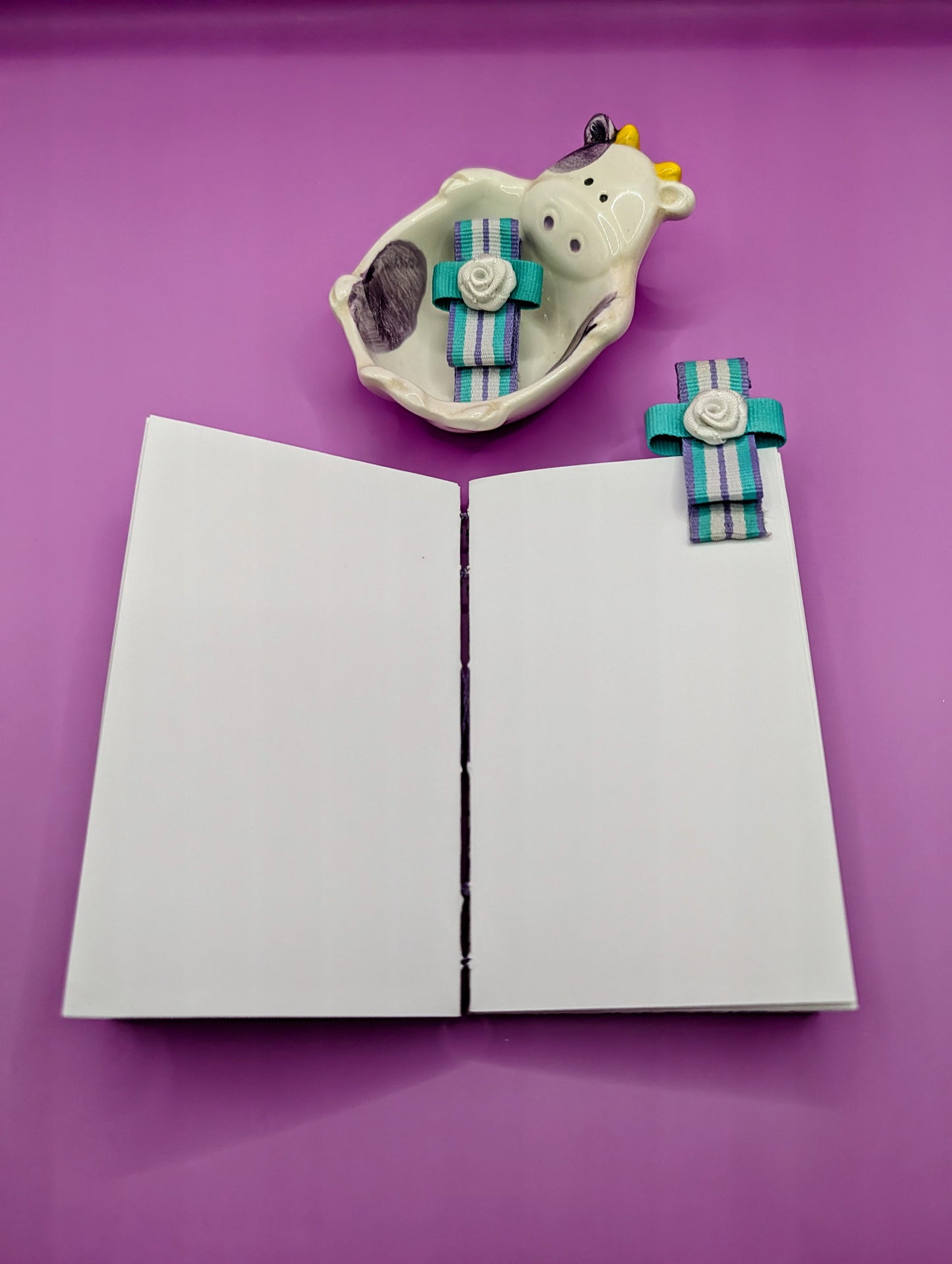 Handmade mini sketchbook featuring purple embossed flowers (Italian paper) and a decorative purple French Stitch. Shown the sketchbook laying flat completely.