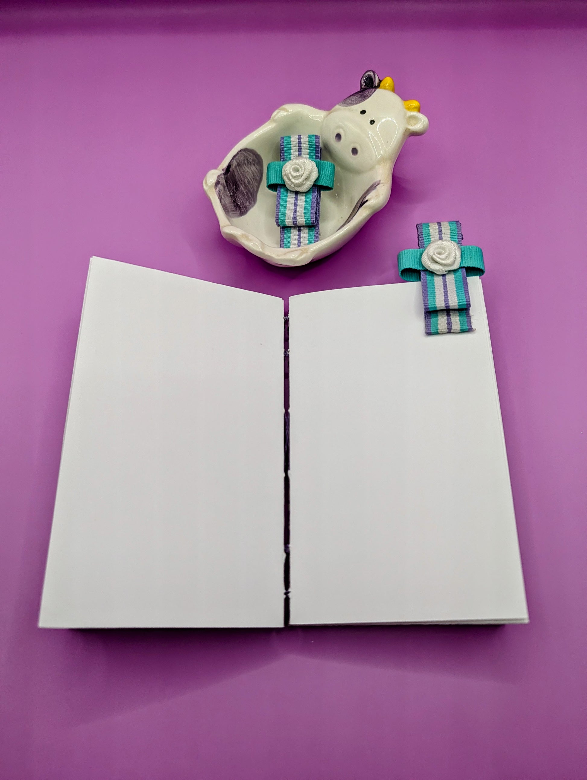 Handmade mini sketchbook featuring purple embossed flowers (Italian paper) and a decorative purple French Stitch. Shown the sketchbook laying flat completely.