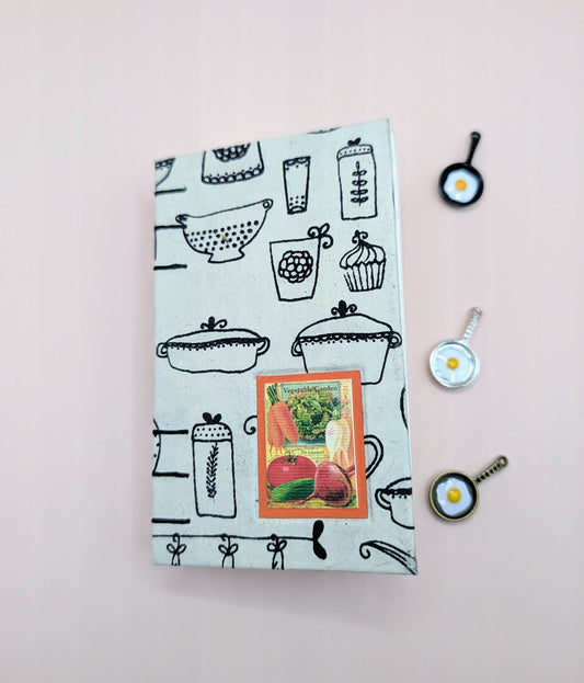 Handmade mini sketchbook with print of utensils, paper is from Nepal. Featuring a beautiful image of veggies on the front. Cold press paper, acid free. Shown front cover.