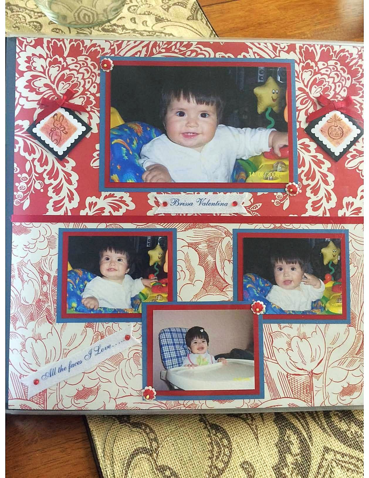 Handcrafted 12x12 baby girl scrapbook page featuring four framed baby photos, red floral patterned paper, diamond accent embellishments, and small banners reading "Brissa Valentina" and "All the faces I love..."