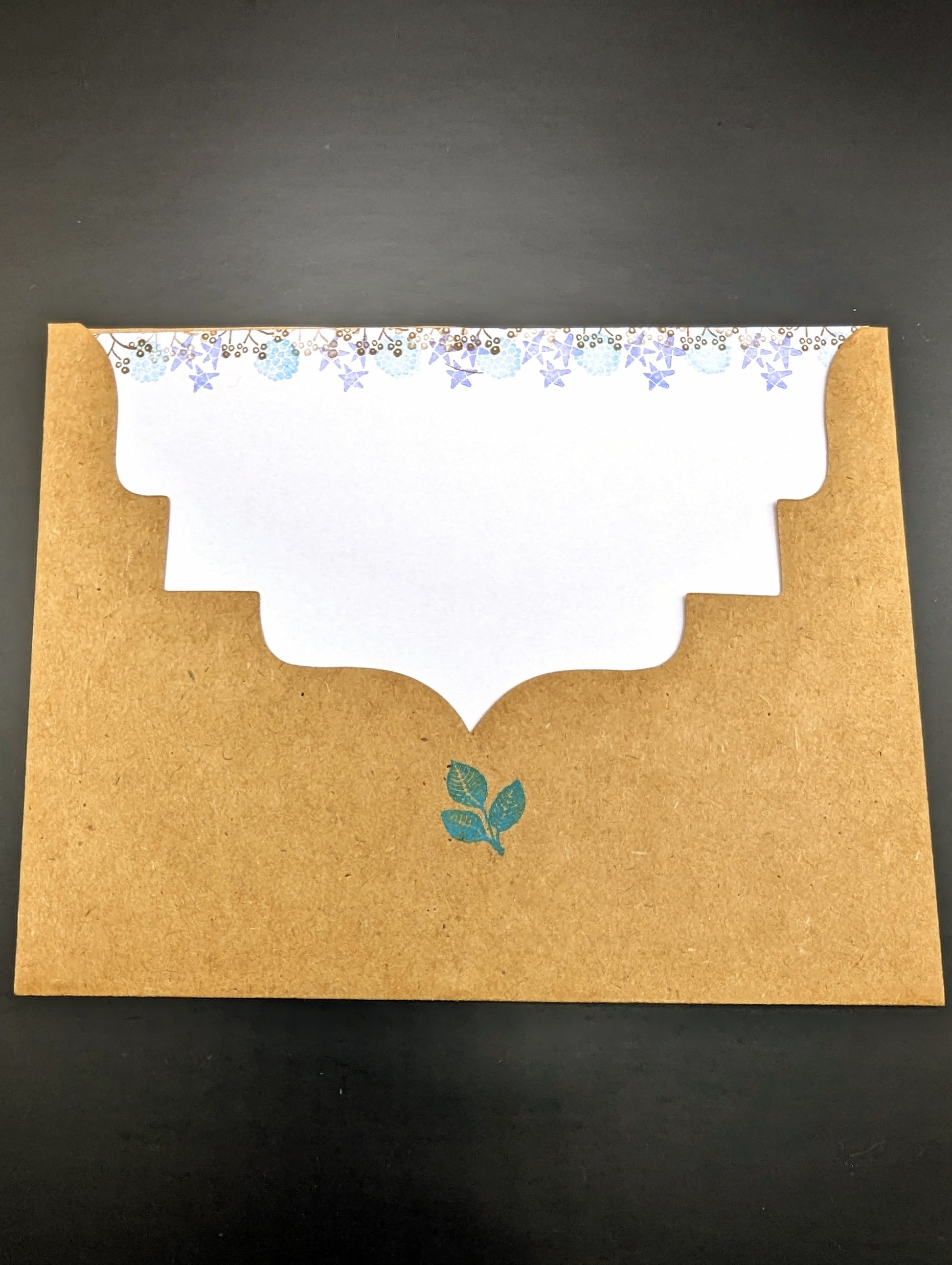 Handmade stationery card with a design resembling an autumn leaf on a brown background, paired with a beige envelope.